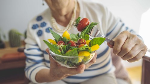 Eine Frau hält Schüssel mit Salat in der Hand